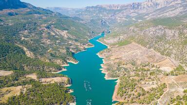 A river winding through a mountainous landscape with dense forests and agricultural fields.
