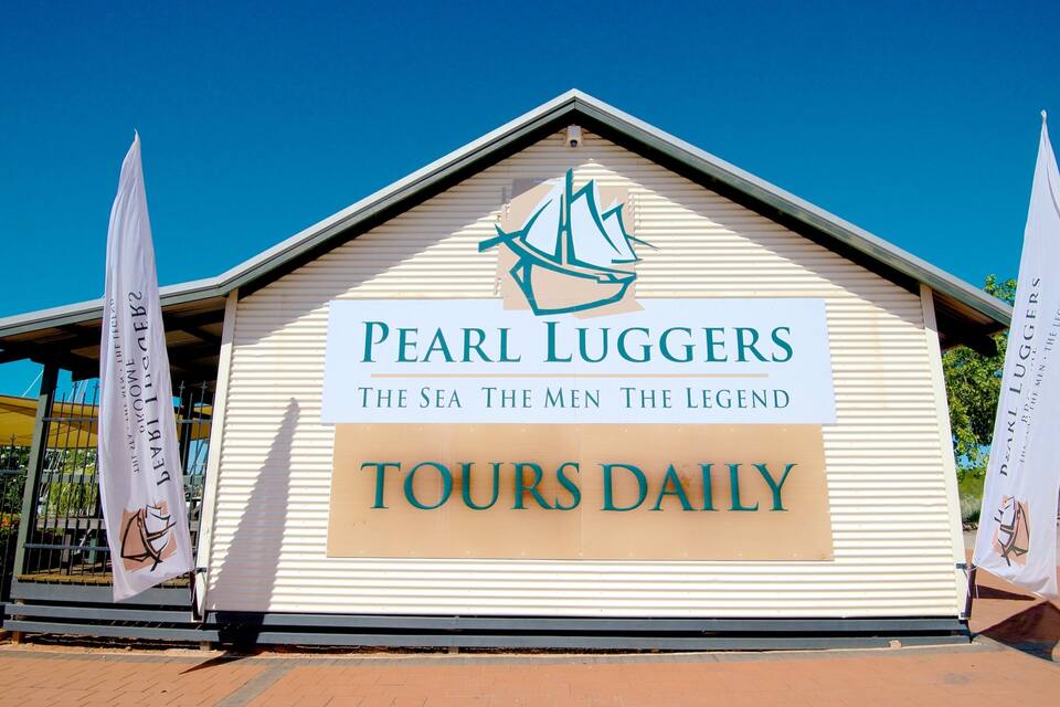 A building with a sign that reads "Pearl Luggers The Sea The Men The Legend Tours Daily" and a sailboat logo.
