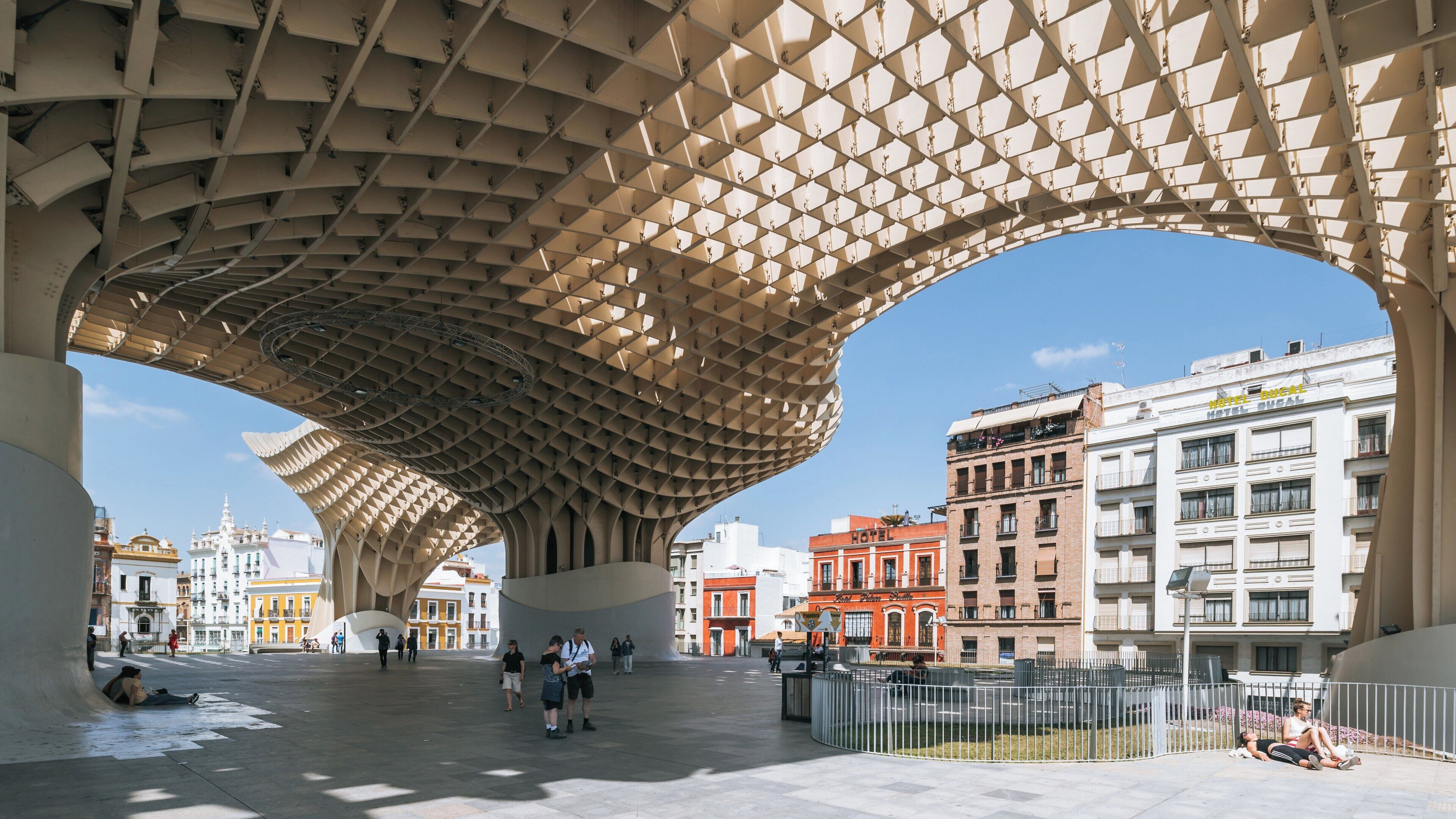 Exploration of Metropol Parasol structure in Historical Center of Seville, Andalusia on a sunny day with visitors strolling and relaxing beneath modern architecture