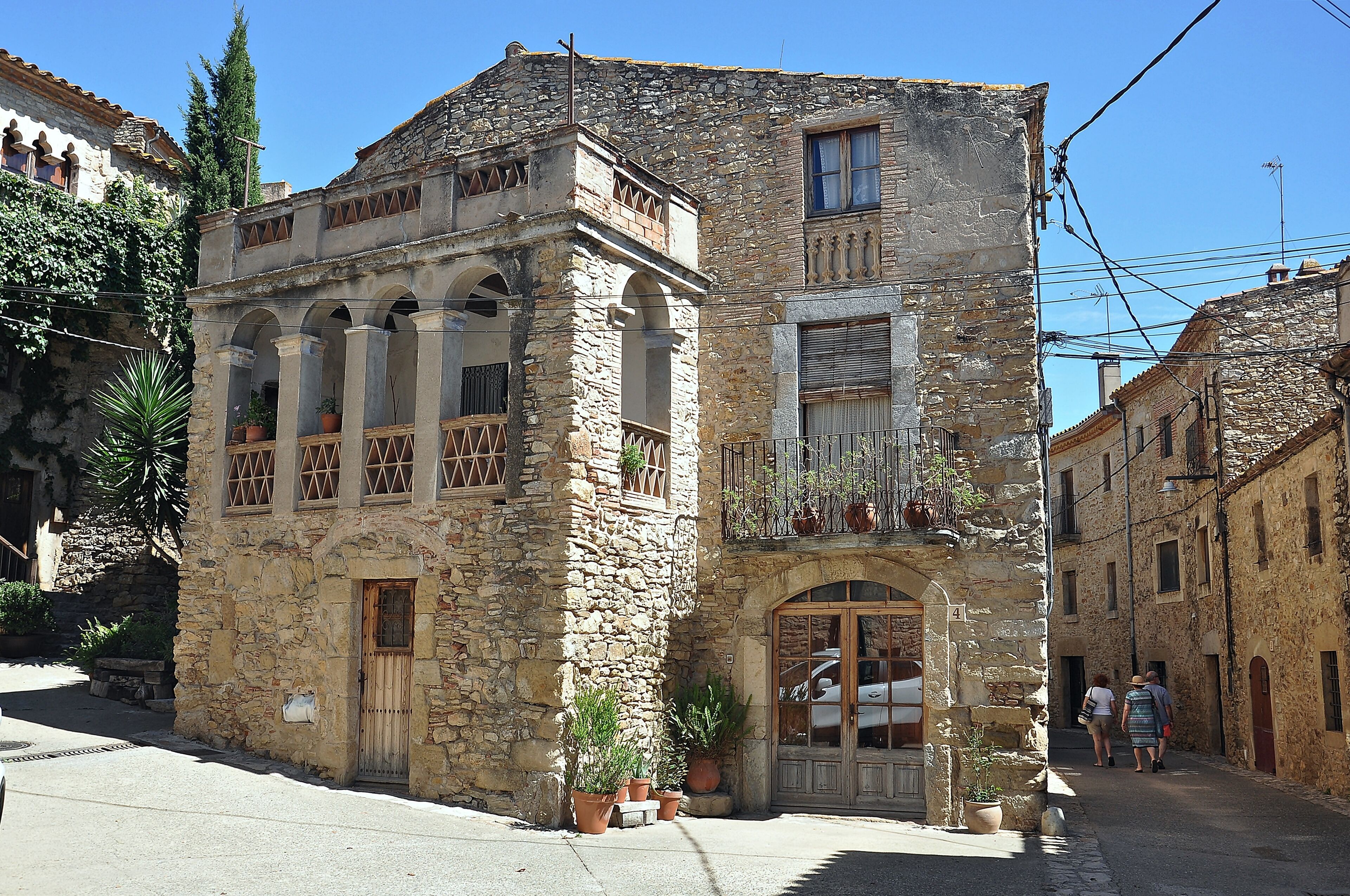 A stone building with arched windows and balconies, surrounded by narrow streets and other historic buildings.