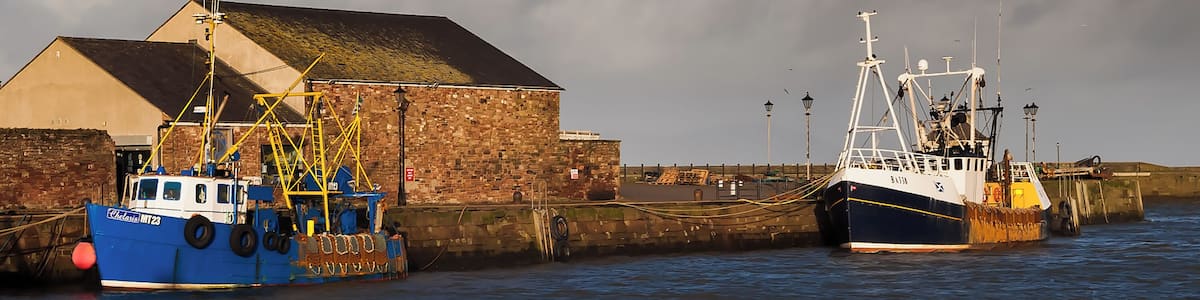 Zwei Boote liegen im Hafen vor einem Backsteinhaus.