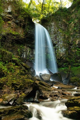 Uma cascata deslizando sobre rochas em uma área arborizada.
