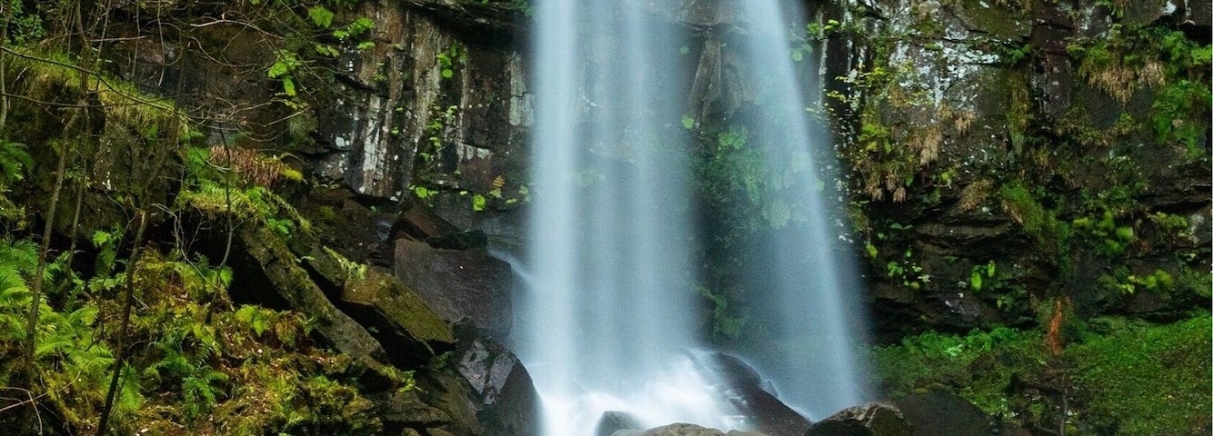 Uma cascata deslizando sobre rochas em uma área arborizada.