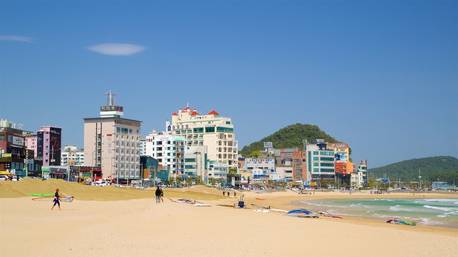 A beach with a cityscape in the background, including hotels and buildings.