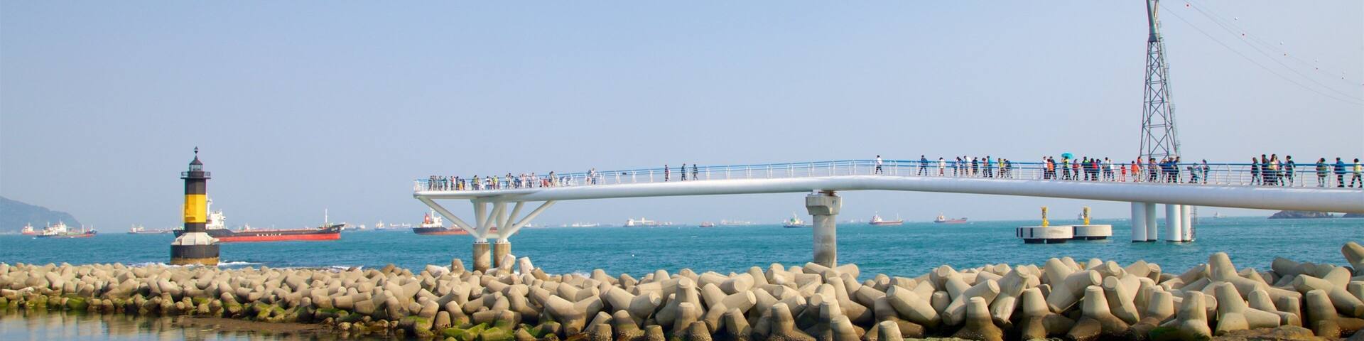 A bridge over water with a lighthouse in the background.