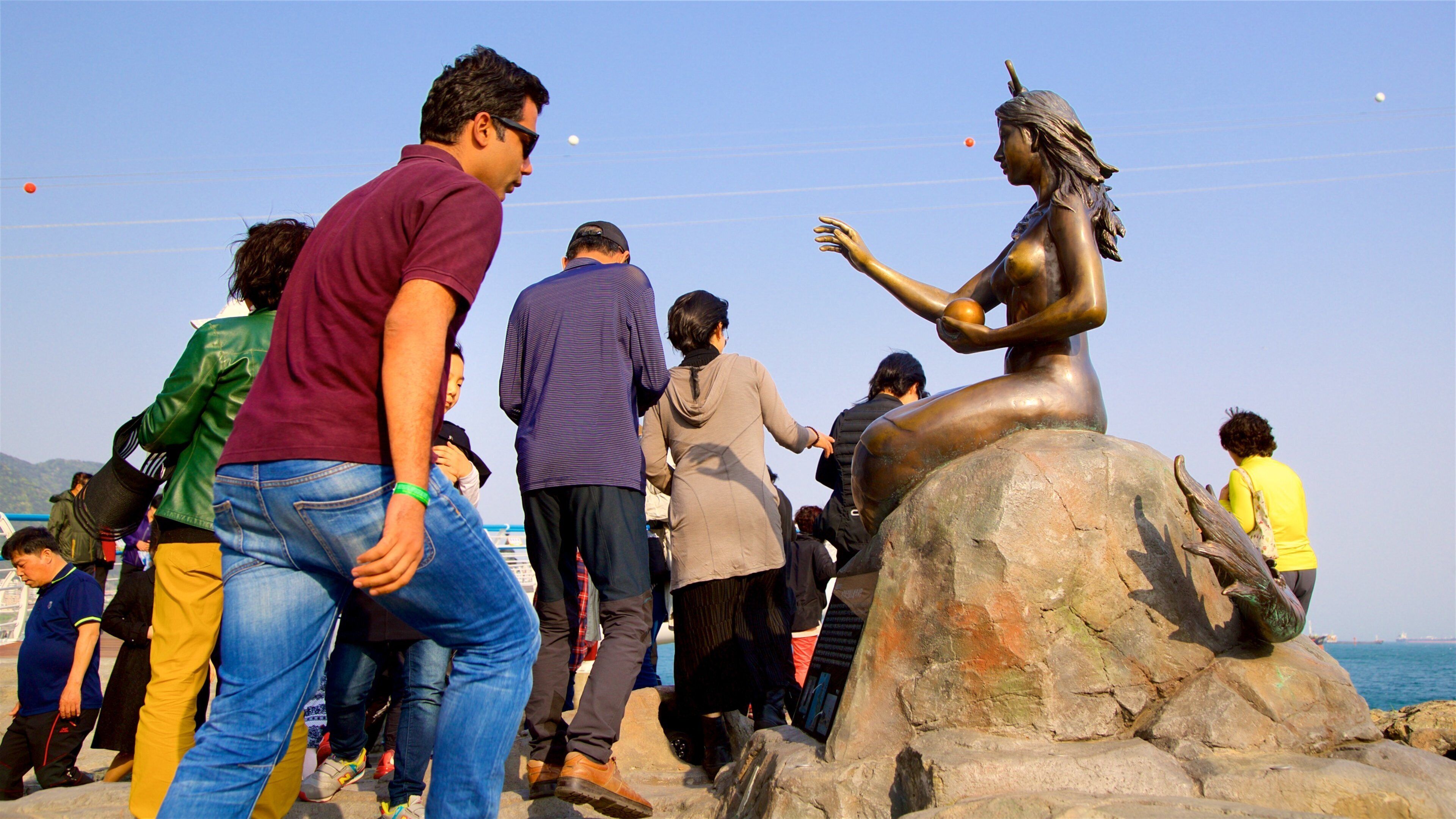 Songdo Beach showing outdoor art and rugged coastline as well as a small group of people