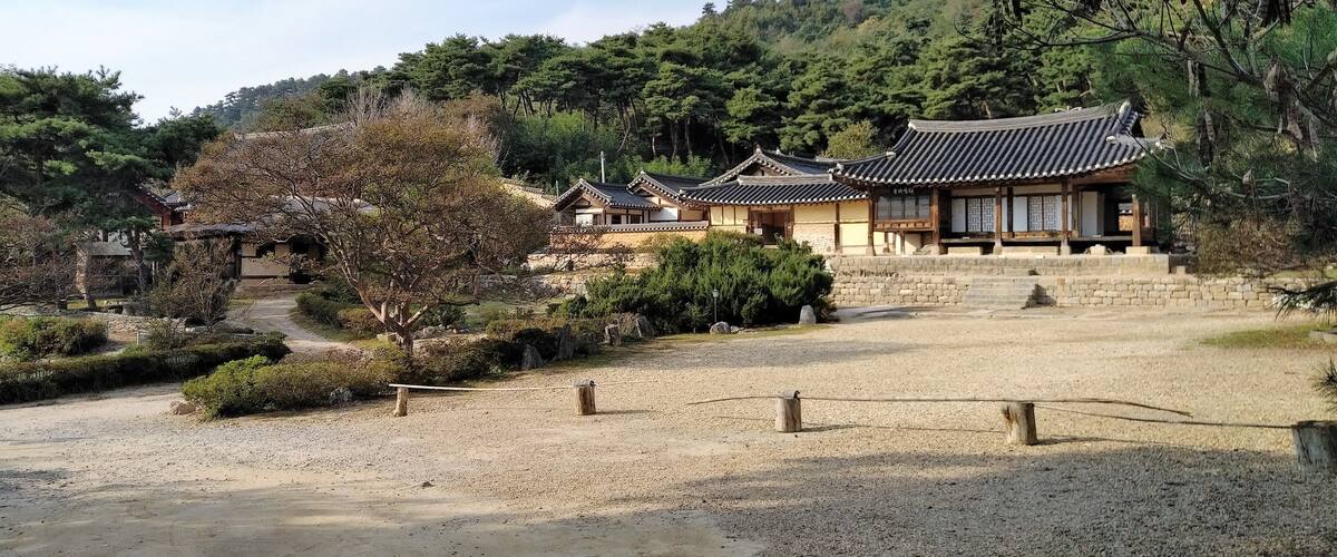 A traditional Korean temple complex with wooden buildings and a gravel courtyard.