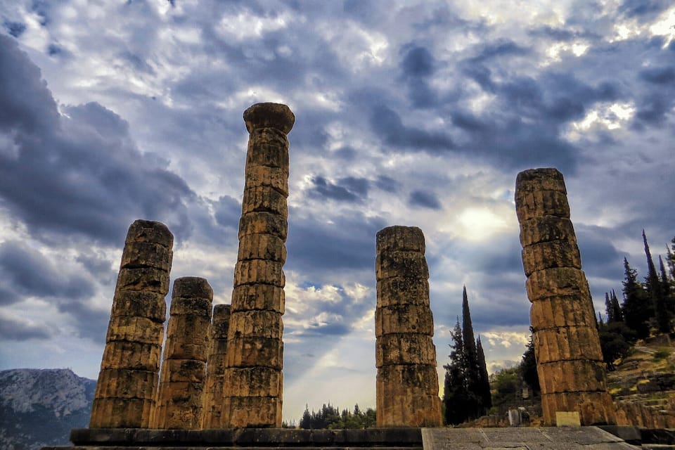 Anciennes colonnes de pierre dans un site historique, sous un ciel nuageux.