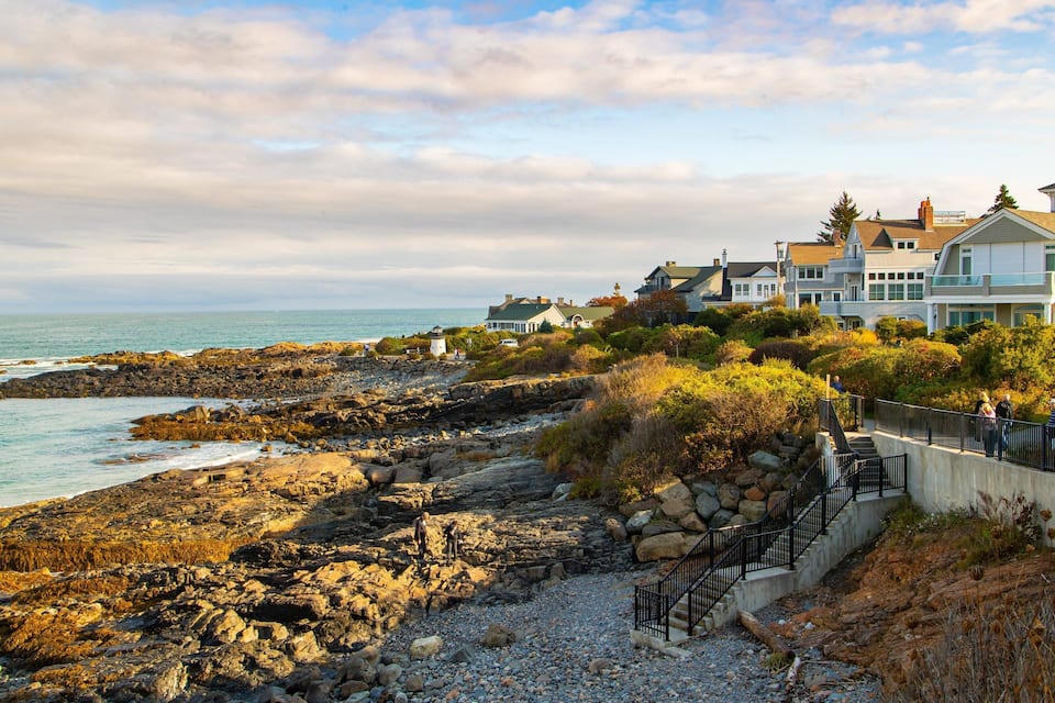 A rocky shoreline with houses and a lighthouse.