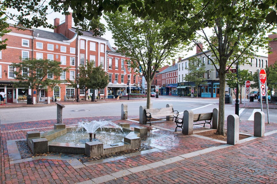 A public square with a water fountain, benches, and a stop sign.