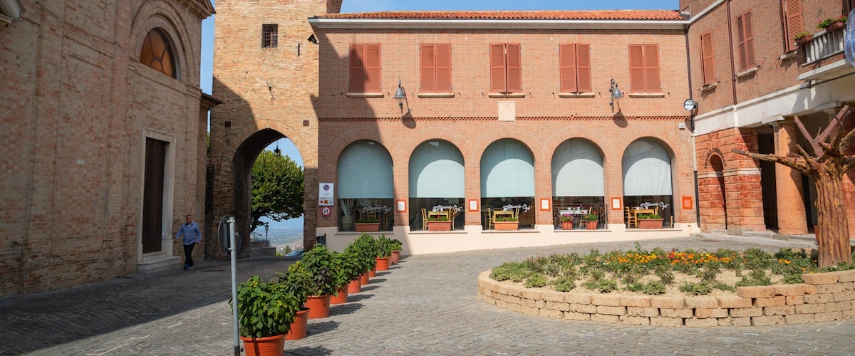 A historic square with a central building featuring arched windows and a tower.