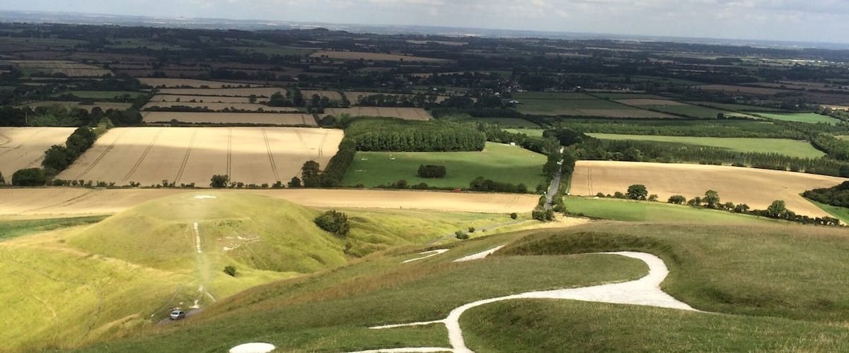 A rural landscape with rolling hills, fields, and a winding road.