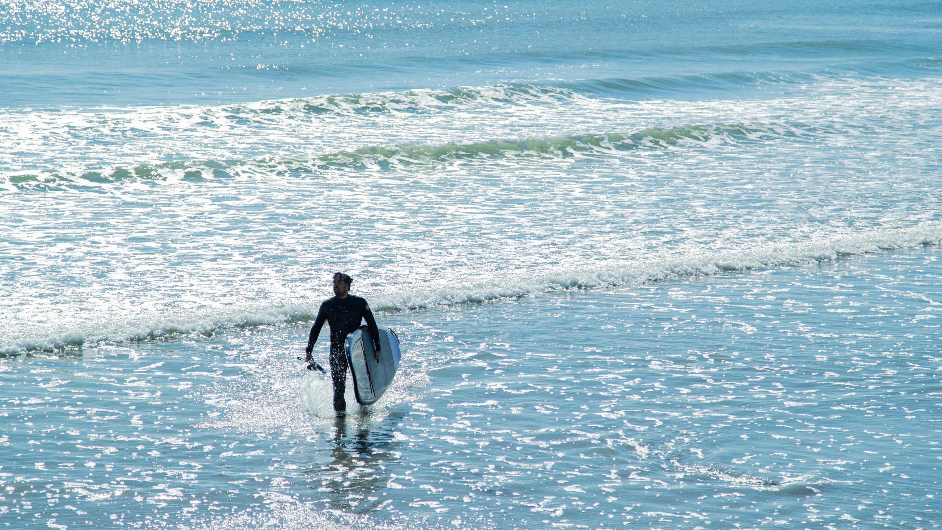 Long Sands Beach featuring general coastal views and surfing as well as an individual male