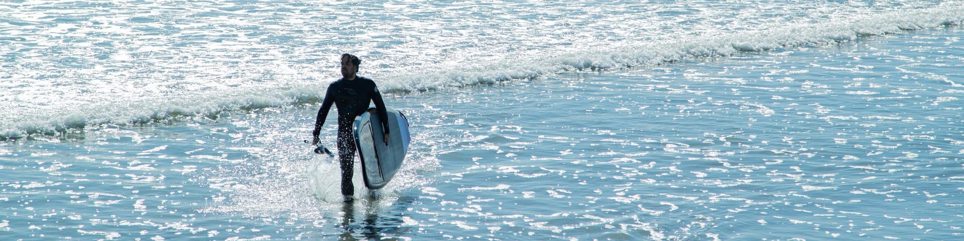 Long Sands Beach featuring general coastal views and surfing as well as an individual male
