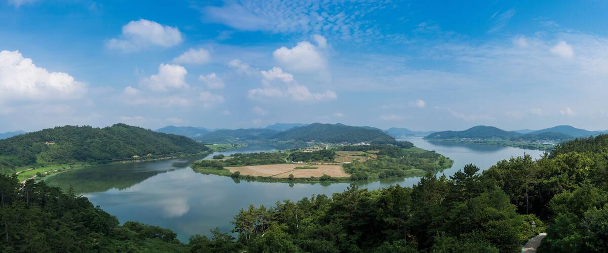 A river winding through a mountainous landscape with dense forests and a clear sky.