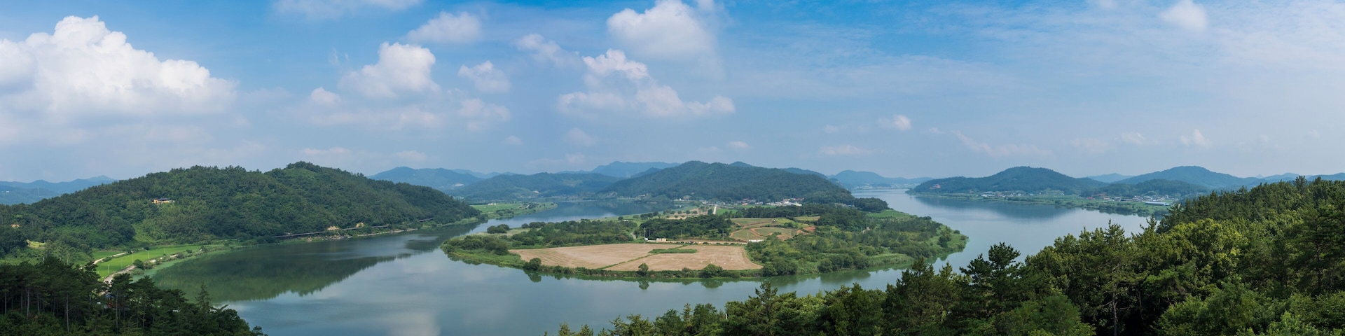 A river winding through a mountainous landscape with dense forests and a clear sky.