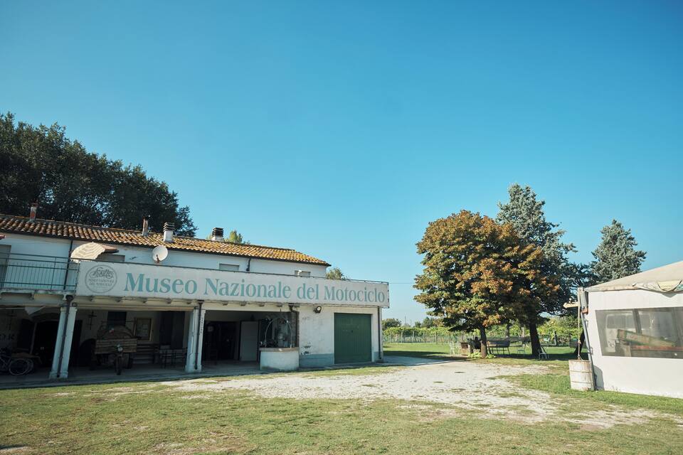A museum with a tiled roof and a green door, surrounded by trees and a clear sky.