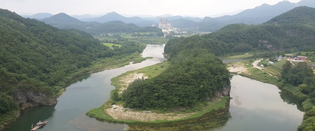 A river winding through a lush valley with mountains in the background.