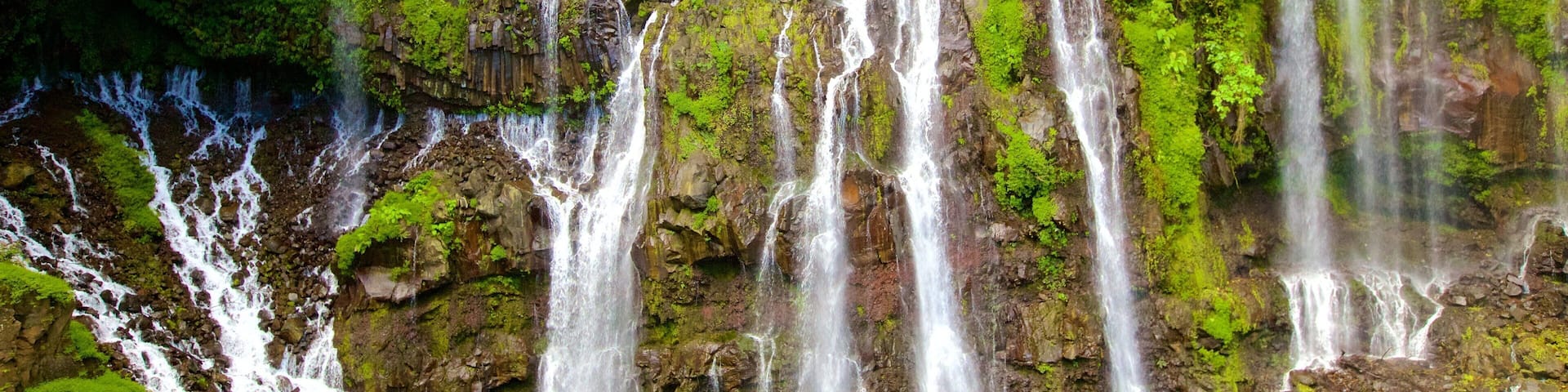 Una cascada en varios niveles que se precipita en una poza cristalina rodeada de exuberante vegetación.