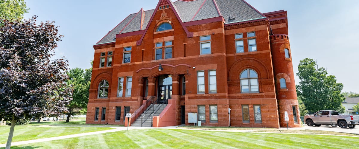 A large brick building with a clock tower and a staircase leading to the entrance.