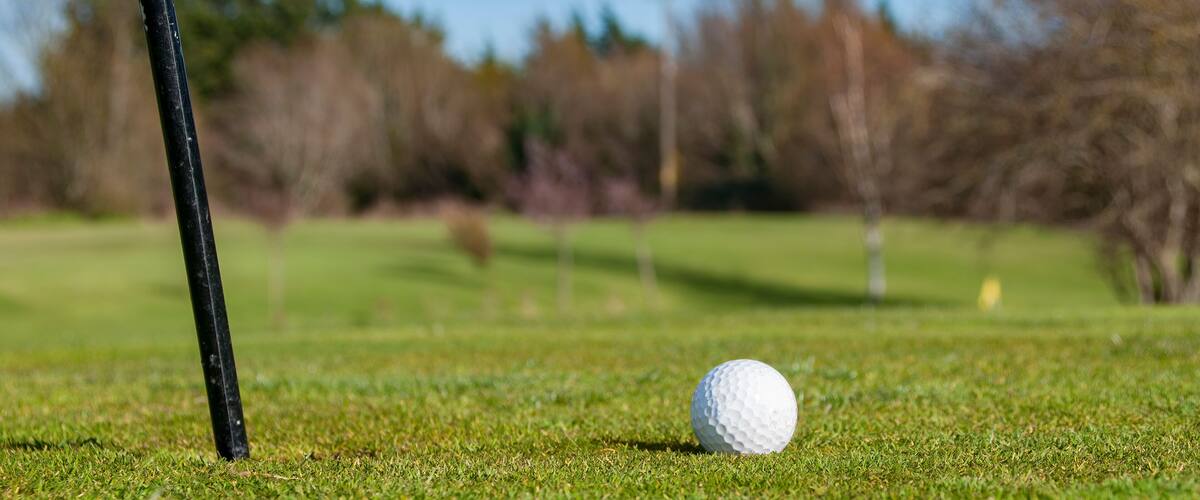 Closeup of Golf Ball beside flagstick.