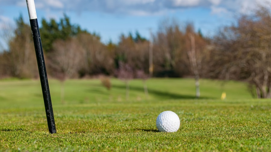 Closeup of Golf Ball beside flagstick.