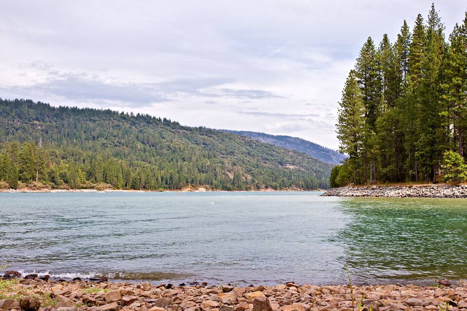A calm lake surrounded by dense forests and hills.