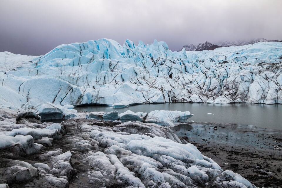 A glacier with icebergs and a calm lake.