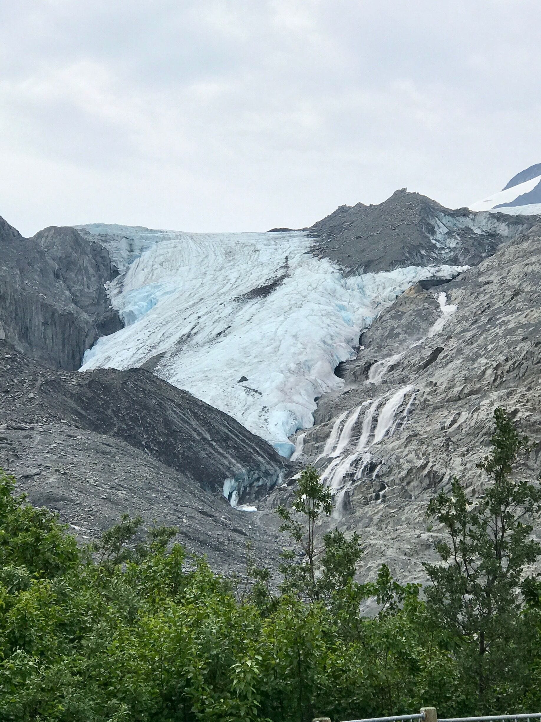 A glacier with a waterfall cascading down a rocky slope.
