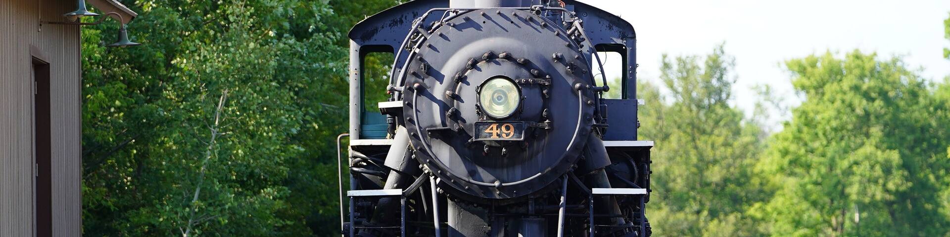 A vintage old 1800s steam train engine sits at the train museum on display.