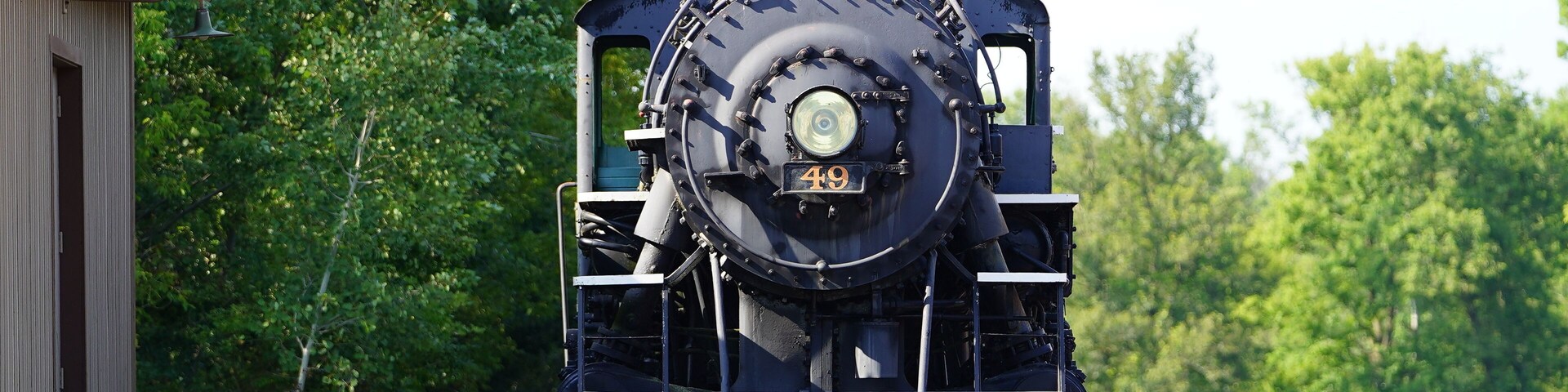 A vintage old 1800s steam train engine sits at the train museum on display.