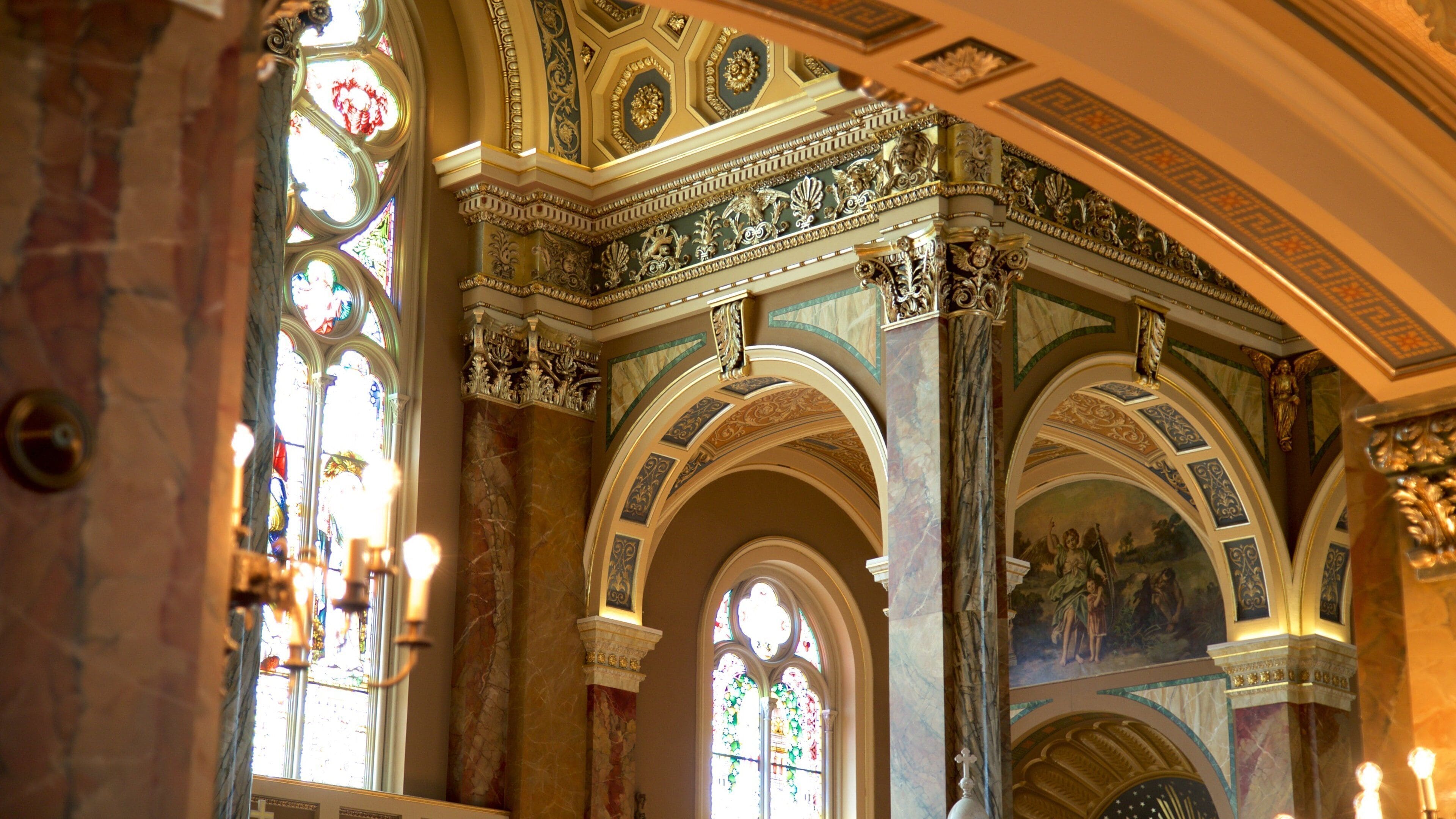 L’intérieur d’une église richement décorée, avec des vitraux, des colonnes de marbre et des fresques détaillées.