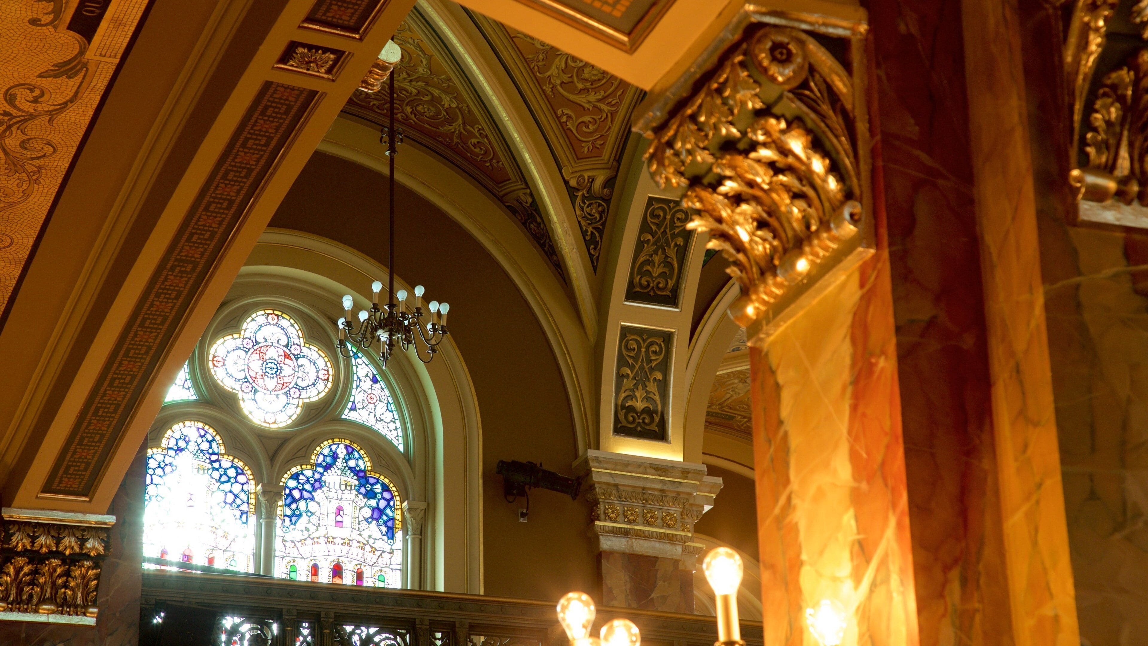 A church interior with ornate stained glass windows and gold detailing.