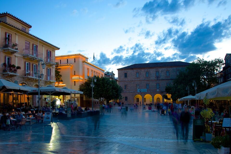 A bustling square with cafes and outdoor seating, historic buildings, and a clear sky.