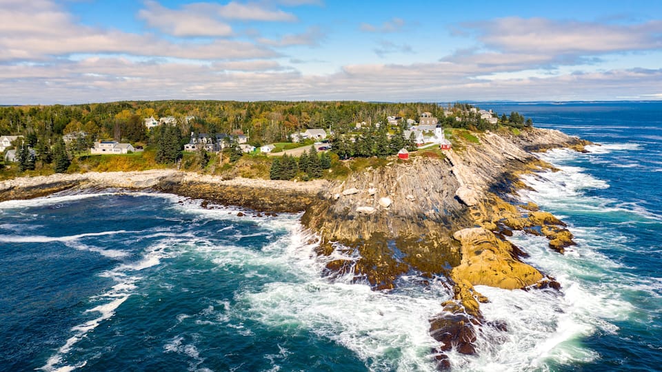 A coastal town with houses, a rocky shoreline, and the ocean.