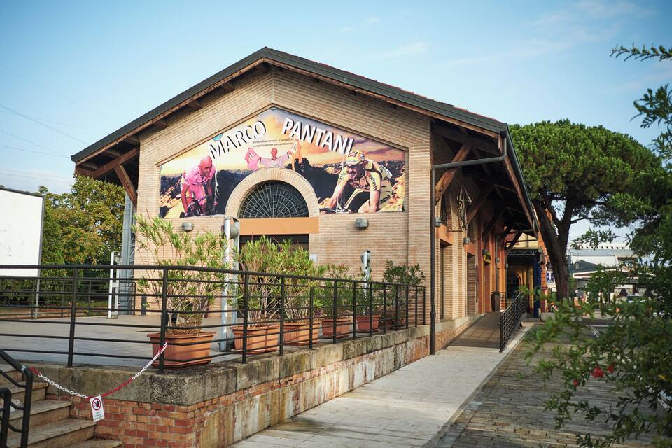 Un edificio con un murale raffigurante un uomo che scala una montagna e la scritta "MARCO PANTANI" sul lato.