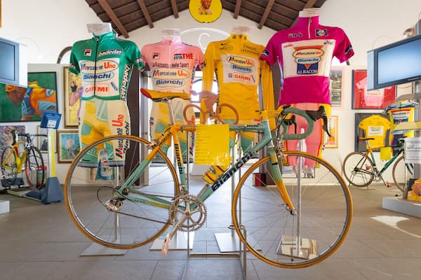 A bicycle in a shop with colorful jerseys hanging in the background.