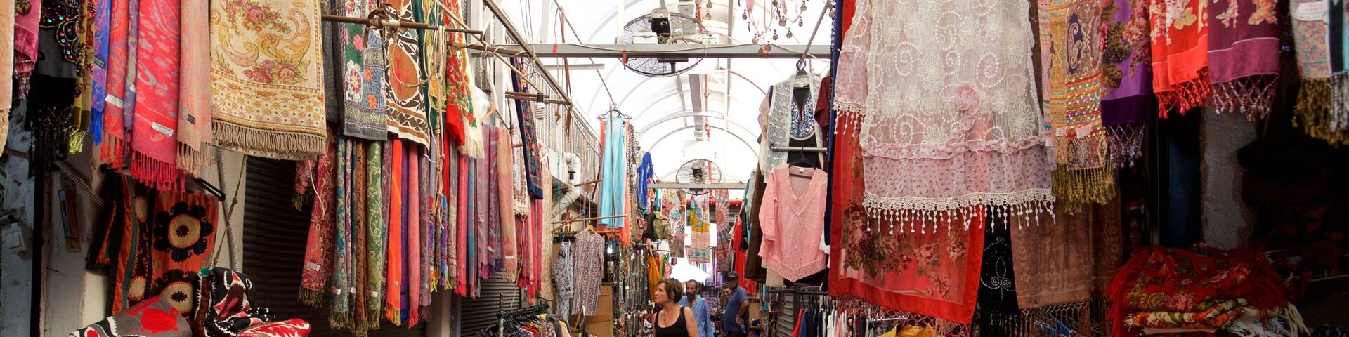 A narrow market aisle filled with colorful textiles and fabrics.