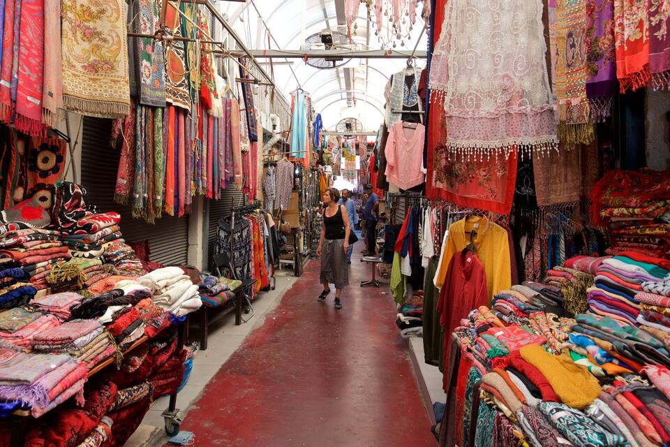 Un corridoio di mercato stretto, pieno di tessuti e stoffe colorate.