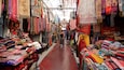 A narrow market aisle filled with colorful textiles and fabrics.