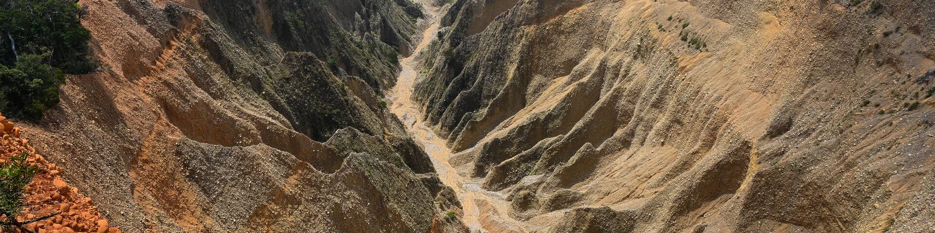 A rugged mountainous landscape with deep valleys and sparse vegetation.