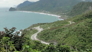 A coastal landscape with a winding road, a mountain, and a beach.