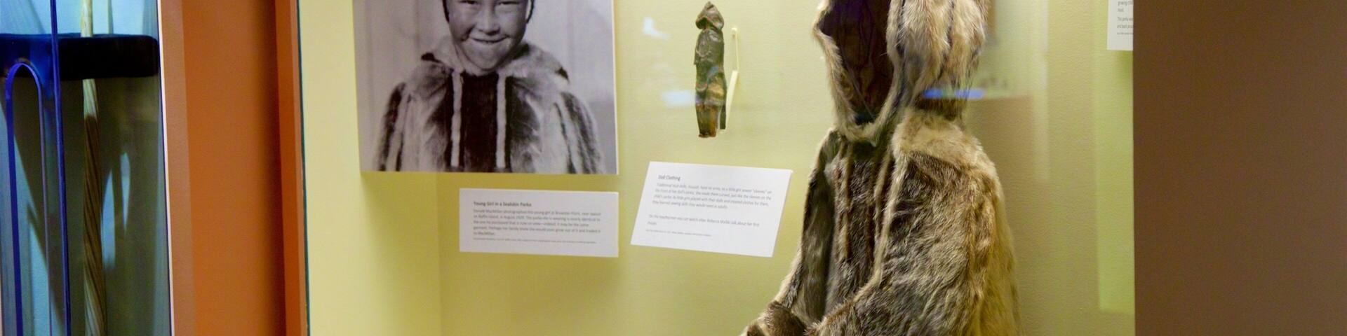 A museum exhibit with a display case containing a traditional garment and informational panels.
