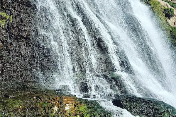 A waterfall cascading over rocky terrain with lush greenery at its base.