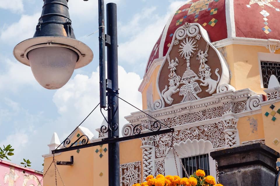A building with ornate white and red domes, a street lamp, and hanging flower baskets.