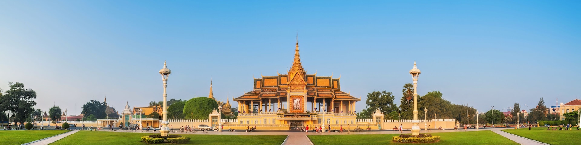 Um templo grande e ornamentado com uma torre central imponente, rodeado por jardins bem cuidados e caminhos.