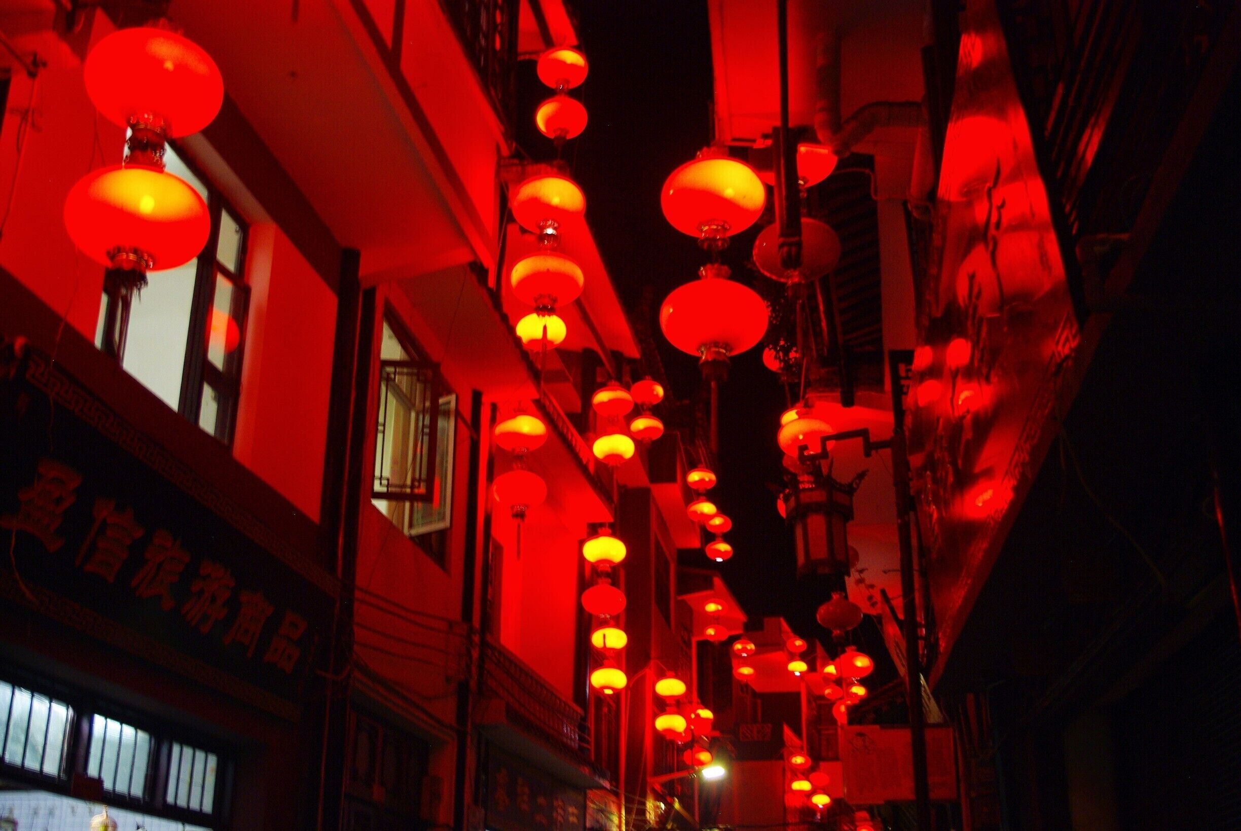A street with red lanterns hanging from the ceiling.