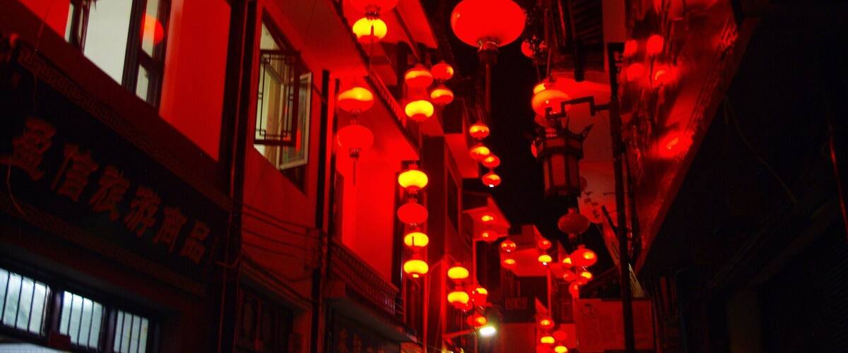 A street with red lanterns hanging from the ceiling.