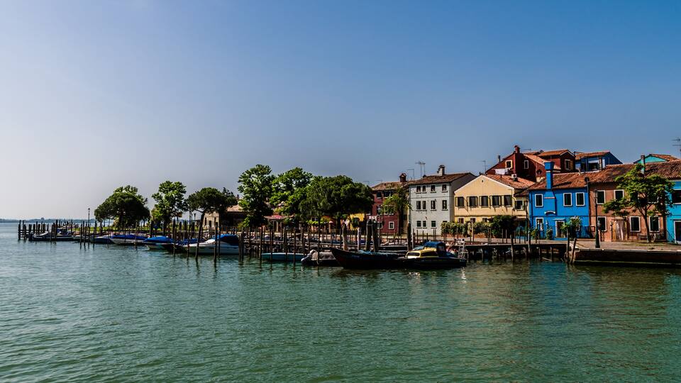 A waterfront with colorful buildings and boats docked along the pier.
