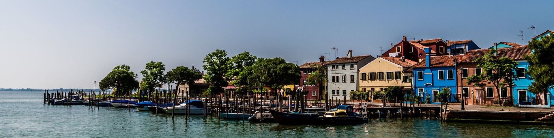 A waterfront with colorful buildings and boats docked along the pier.